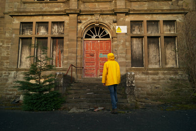 A person in yellow jacket exploring an abandoned building